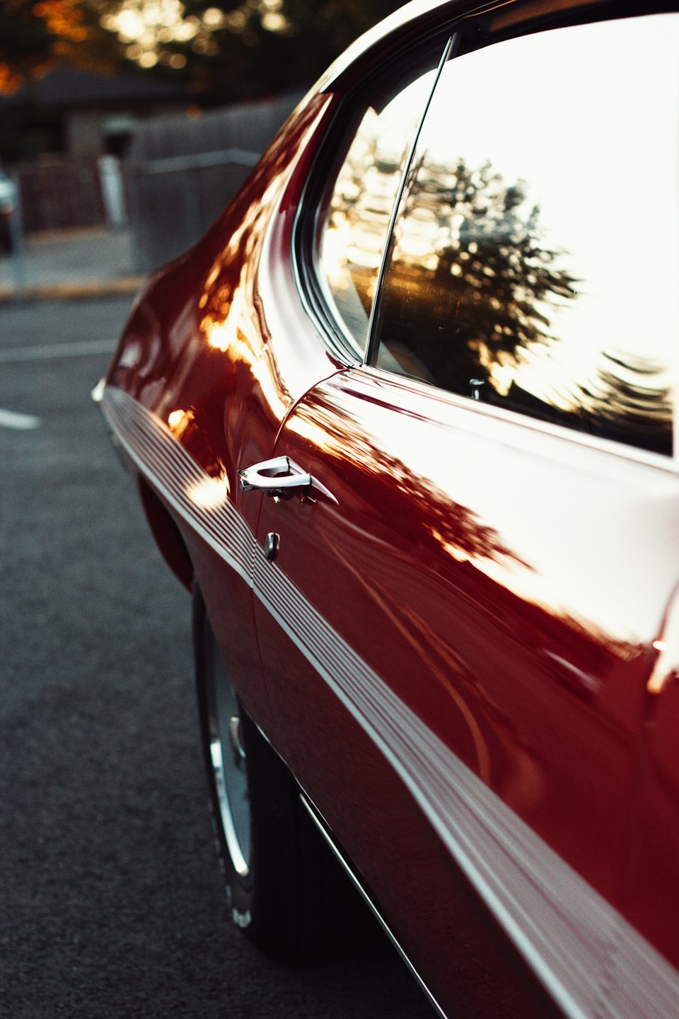 Side profile of a red vintage car with white racing stripes.