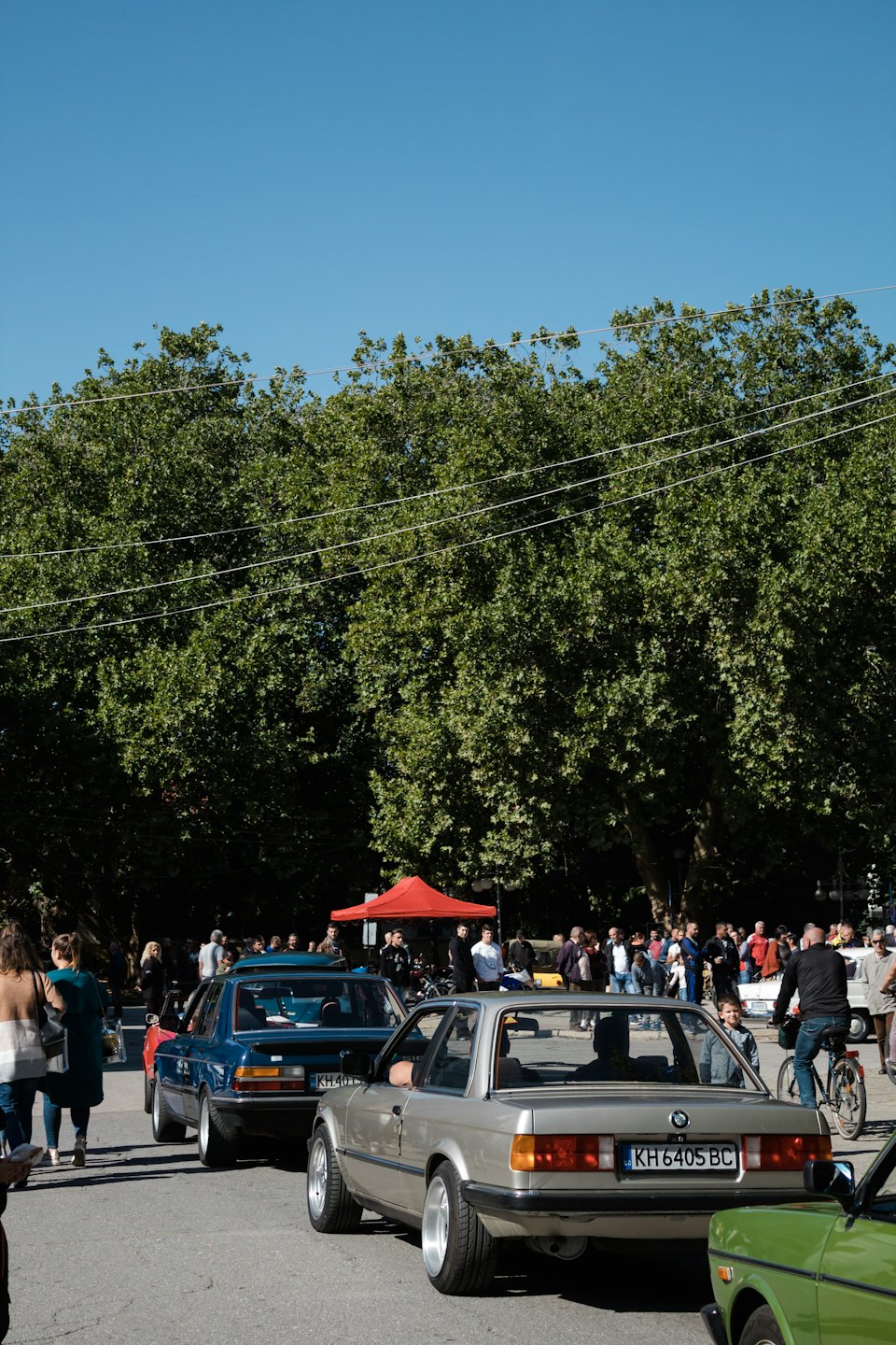 People walking between vintage cars at an outdoor show.